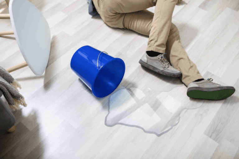 Person lying on ground after slipping on spilled bucket of water and knocking over a table before talking with a Premises Liability Lawyer Anaheim, CA
