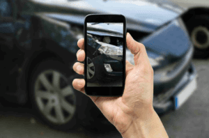 Hand holding phone taking a photo of damage for a Rideshare Accident Lawyer Anaheim, CA